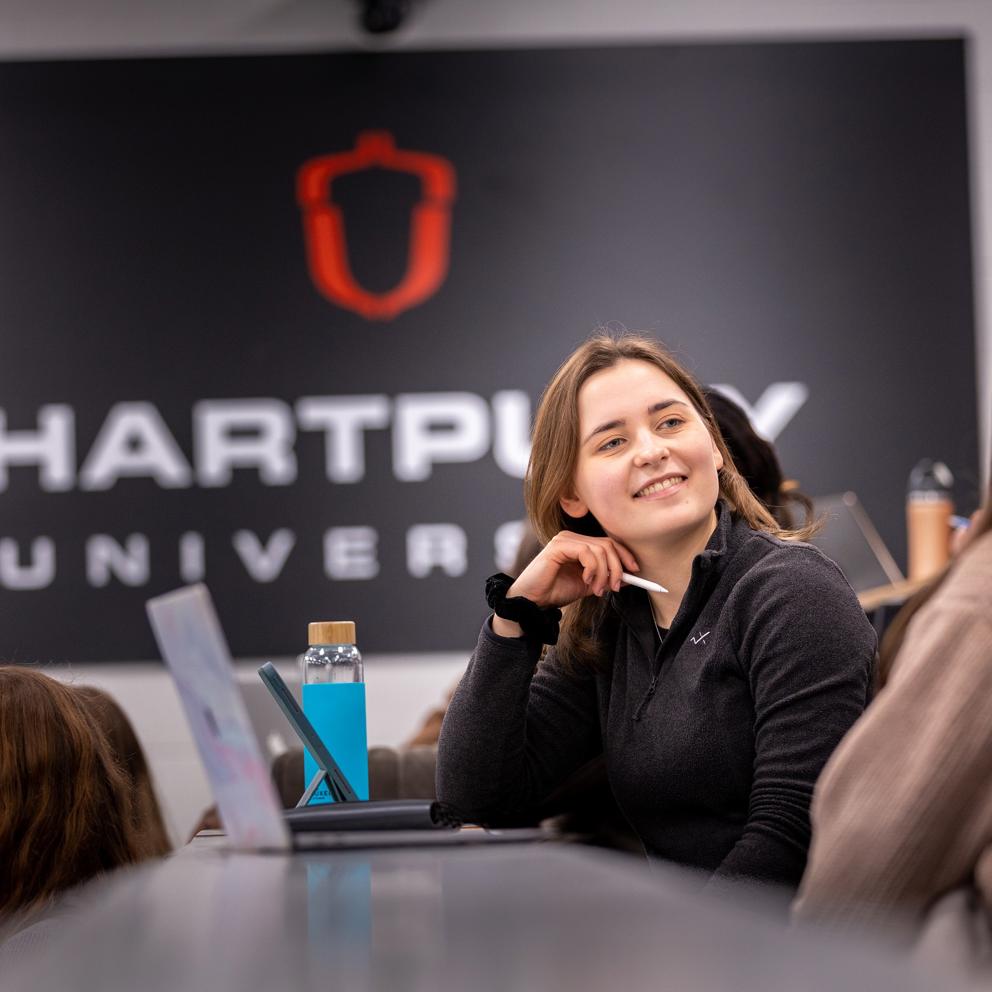 Image of students sat in a lecture theatre with a student smiling at other nearby students