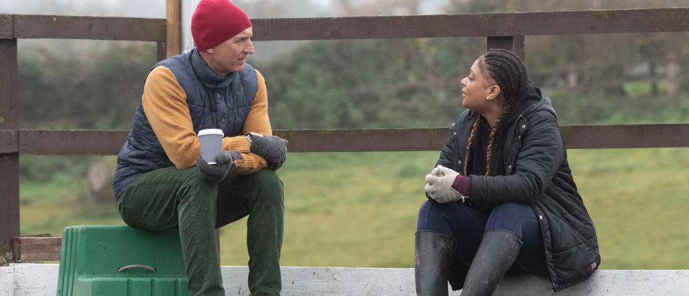 Man And Woman Talking In Equestrian Arena