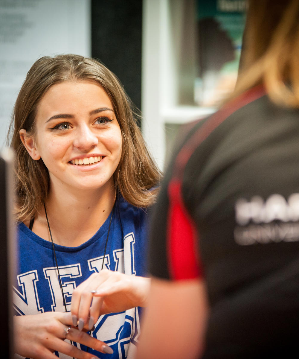 Image of a student smiling at a member of staff sat in front of them