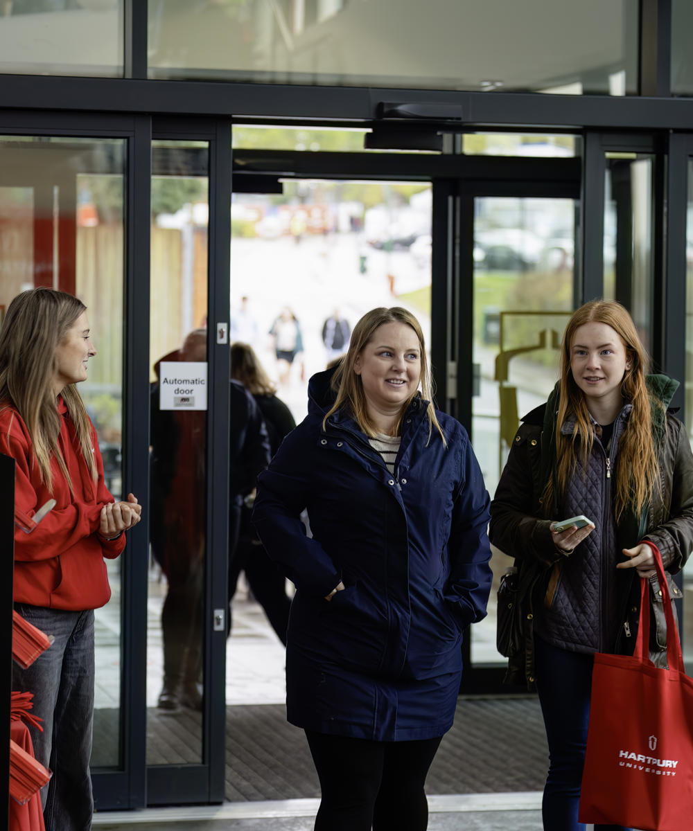 Visitors Walking Through Doors With Gift Bag