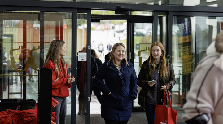 Visitors Walking Through Doors With Gift Bag