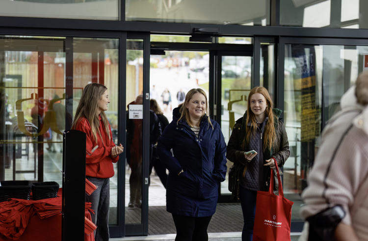 Visitors Walking Through Doors With Gift Bag