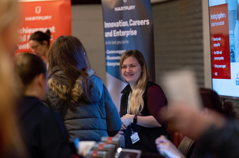 Image of Hartpury University staff member smiling at guests at an applicant event
