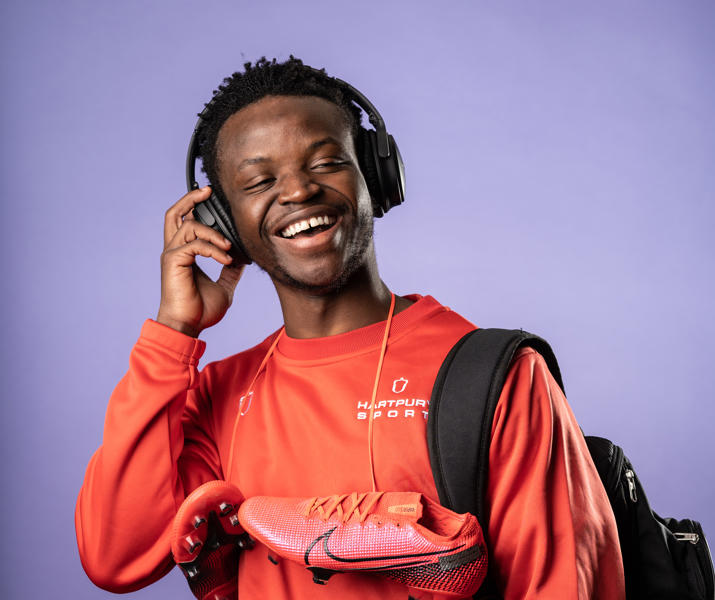 Image of Hartpury University Sport student smiling whilst holding onto their overhead earphones