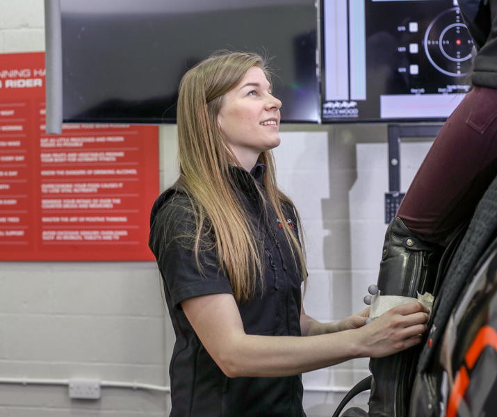 Lady Helping A Rider On Horse Simulator