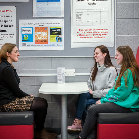 Student Support staff member sat with two students