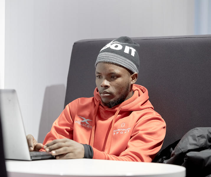 Image of international student working on their laptop in a study booth