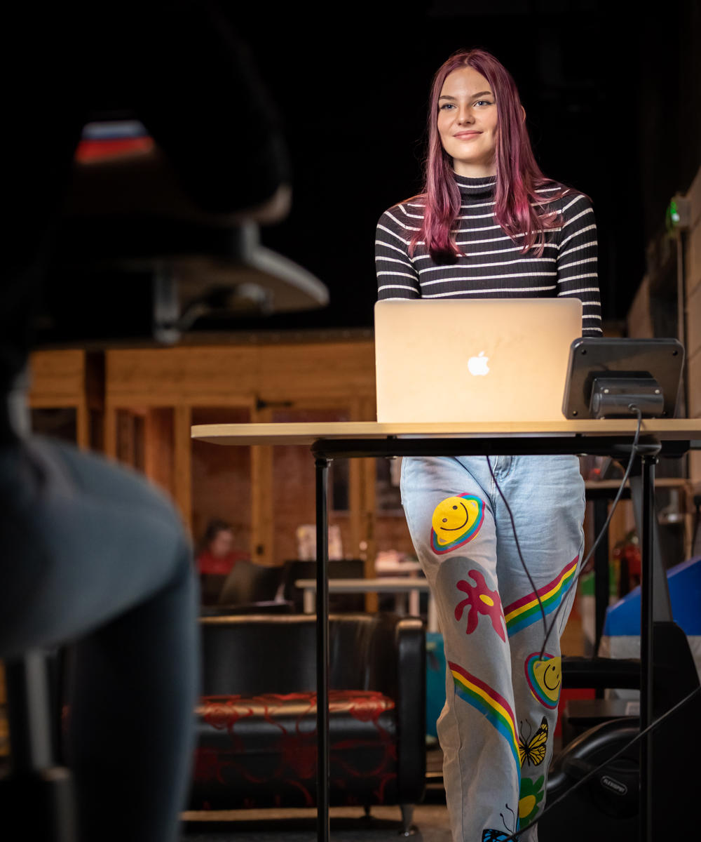 Image of student at a standing desk on their laptop whilst walking on a walking pad